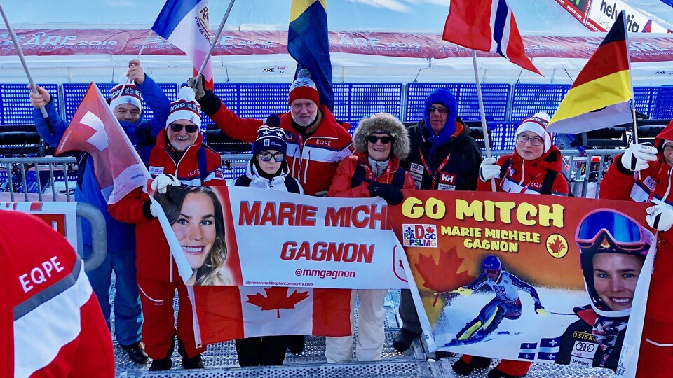 Des supporteurs tiennent des banderoles avec le nom et le visage de Marie-Michèle Gagnon.