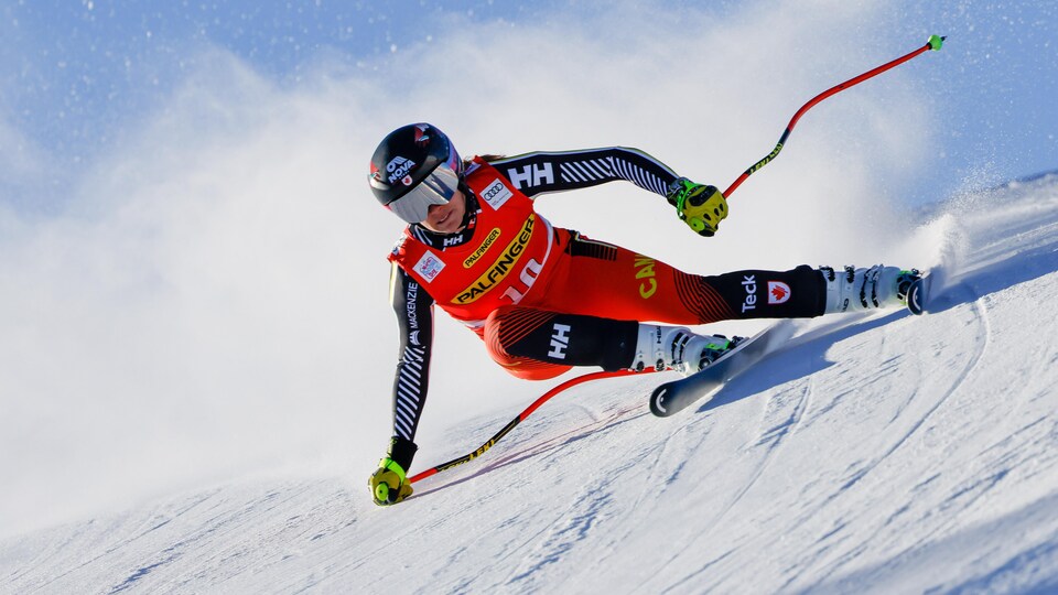 Une skieuse dévale une pente, le poing droit sur la neige.