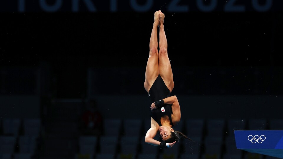 Elle plonge de la tour de 10 m avec une main sur la tête et une autre sur l'abdomen.