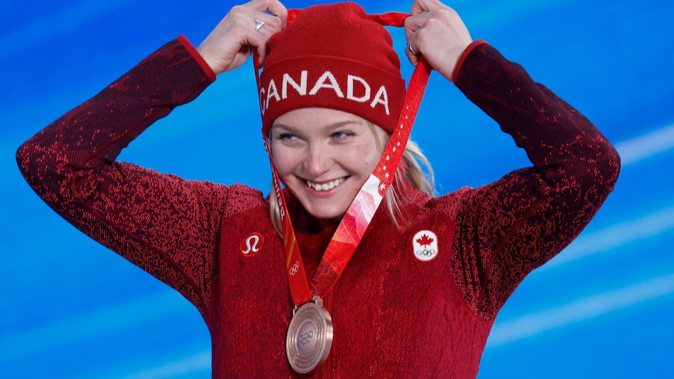 Elle sourit et place la médaille autour de son cou. 