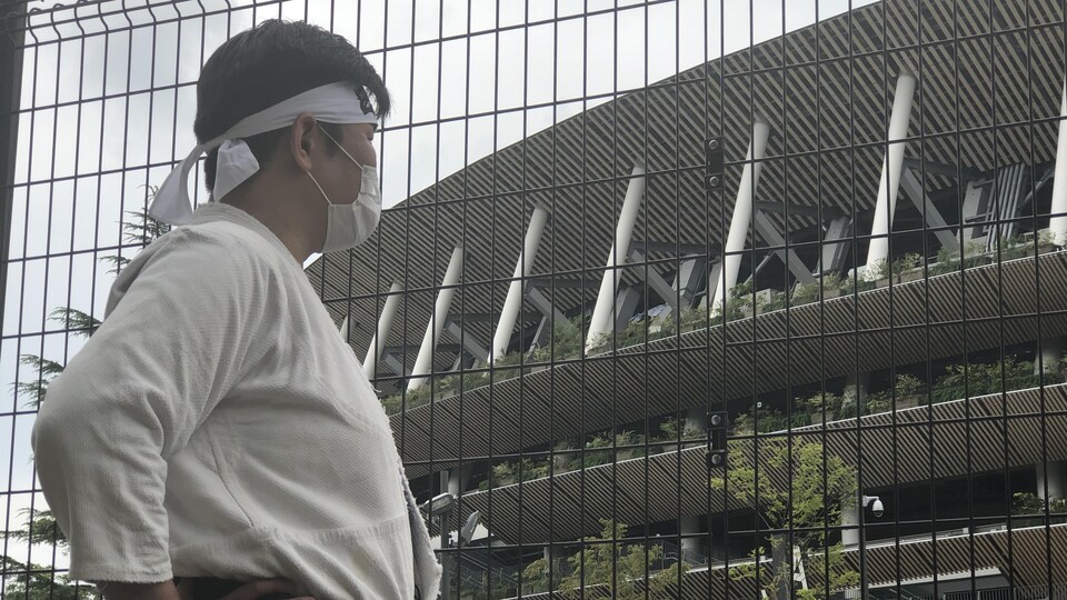 Kazunori devant une clôture.