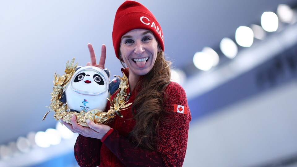 Elle porte une tuque du Canada et montre deux doigts en forme de V.