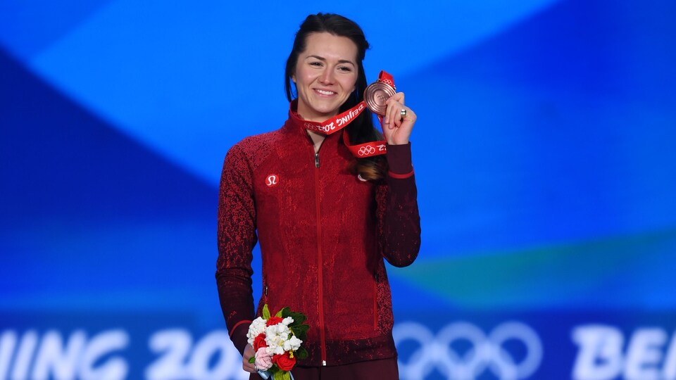 Sur le podium, elle tient sa médaille de bronze dans la main gauche et un bouquet dans la droite.