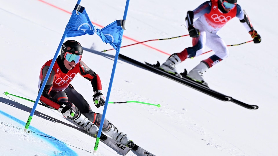 Deux skieurs descendent une piste en parallèle.