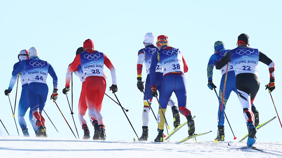 Huit fondeurs en action sur la piste de ski de fond.