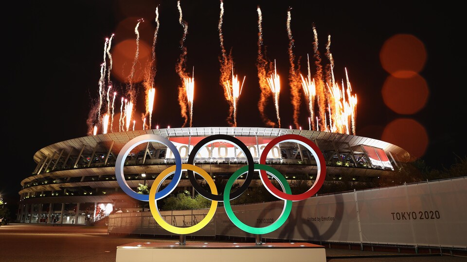 Les anneaux olympiques installés aux abords du stade de Tokyo pendant le lancement de feux d'artifice.