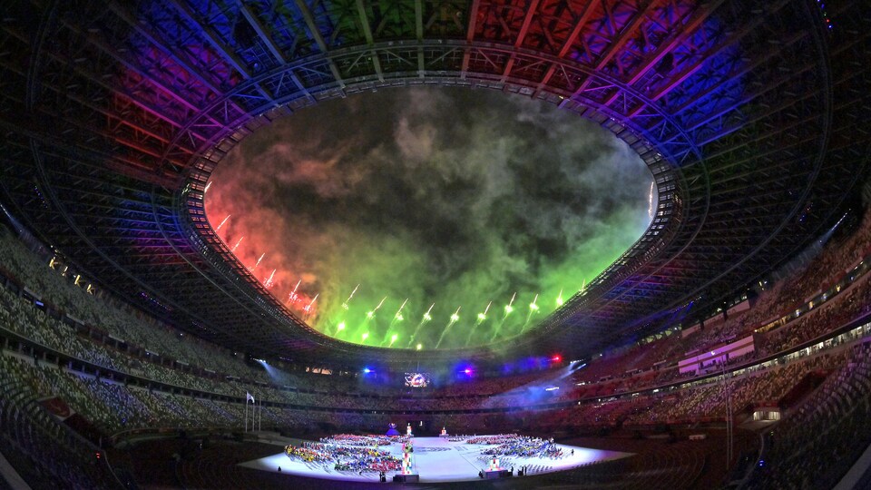 Des feux d'artifice sont projetés hors du stade sous des jeux de lumière.