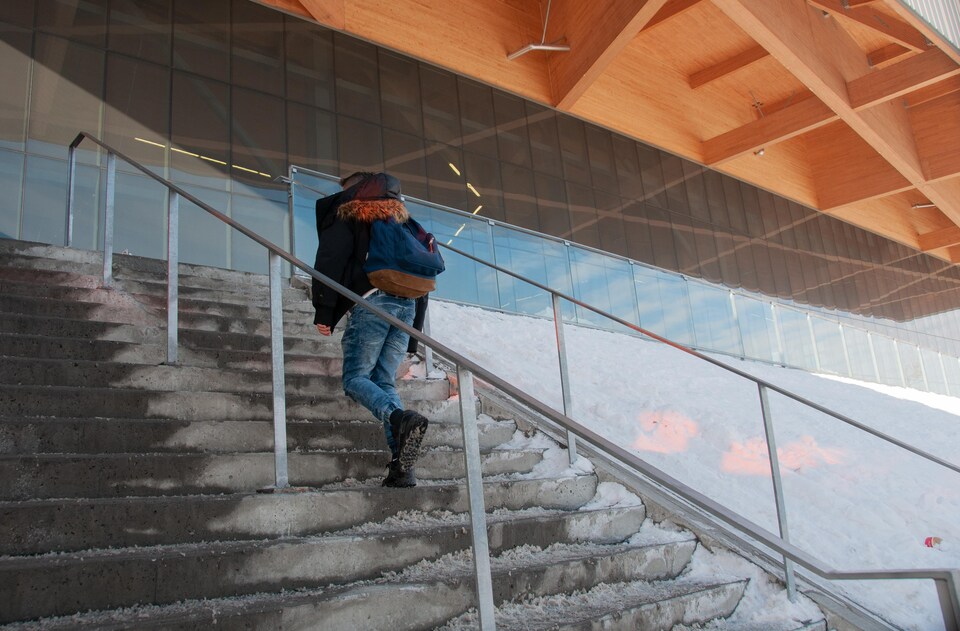 Un adolescent monte les marches d'un escalier à l'extérieur en hiver.