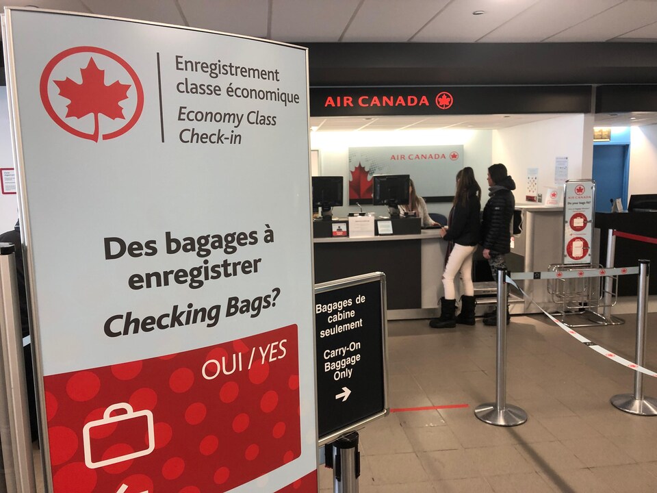 On voit un comptoir dans un aéroport au dessus duquel on peut lire Air Canada.