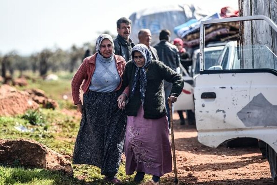 Une femme soutient une personne âgée qui marche pour fuir la ville d'Afrine en Syrie.
