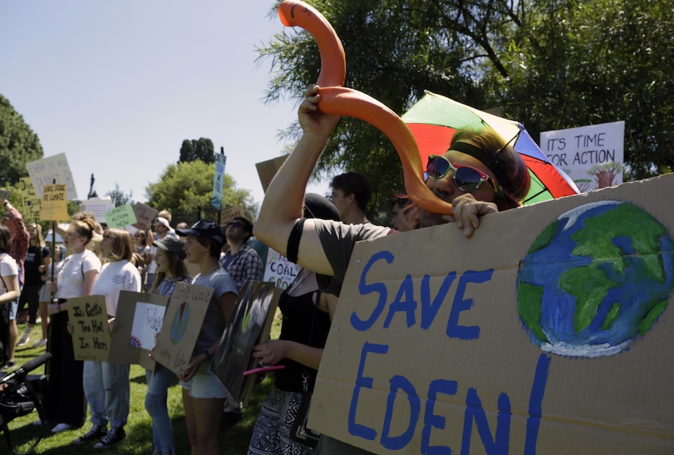 Un étudiant tient une affiche avec le dessin d'une terre et la mention : « Sauver l'Eden ».
