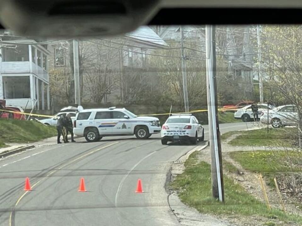 Photo taken from a vehicle that is no longer moving.  The road was blocked by police vehicles and policemen, who put up a yellow cordon blocking the road.