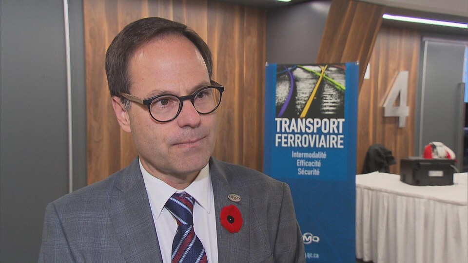 Alexandre Cusson à l'hôtel Delta de Trois-Rivières devant une bannière du forum