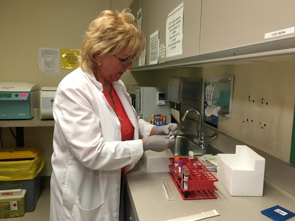 L'infirmière Ginette Chouinard, portant un sarrau blanc, inspecte des fioles rouges dans un local de l'Hôpital Maisonneuve-Rosemont. 