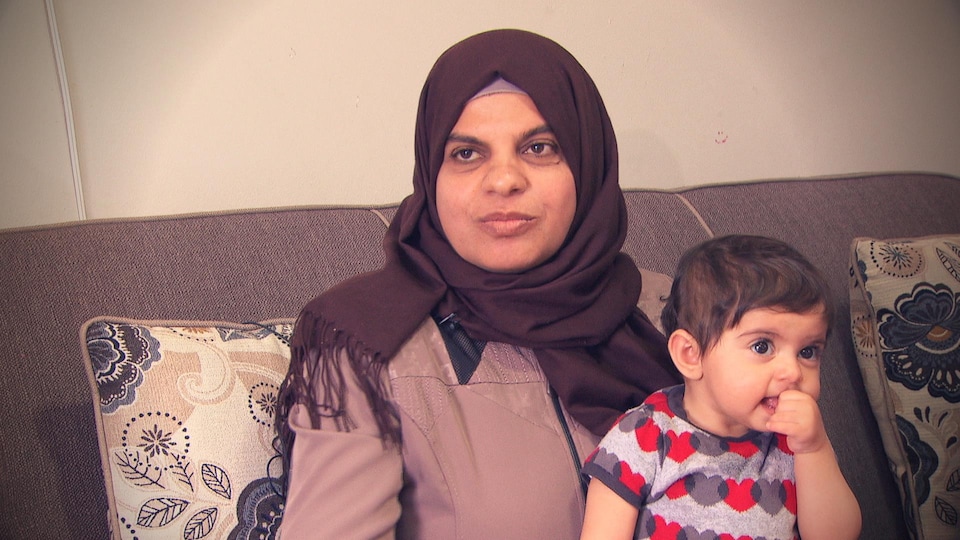 Une femme voilée tient un enfant assis sur ses genoux.