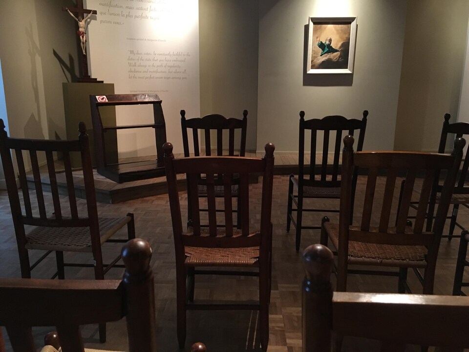 Des chaises sont alignées en direction d'une peinture chrétienne.