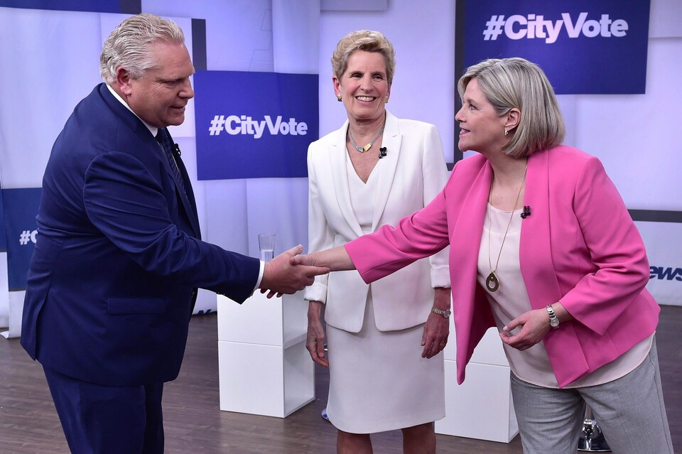 Doug Ford serre la main à Andrea Horwath pendant que Wynne les regarde en souriant.