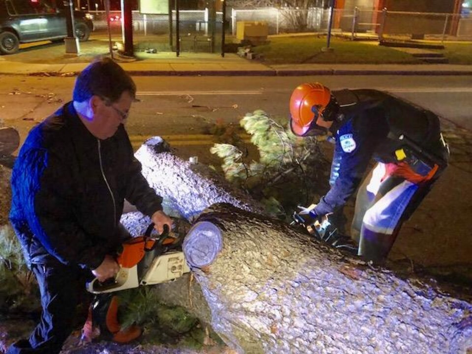 Un citoyen et un policier coupent un arbre qui entrave la chaussée sur le boulevard Alexandre-Taché, dans le secteur de Hull à Gatineau.