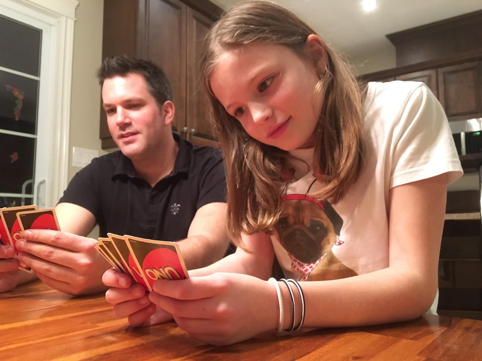 Éric et Ariane assis à une table jouent aux cartes.
