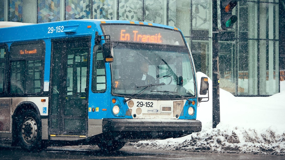 Un autobus de la STM est en transit au centre-ville de Montréal, sous la neige.