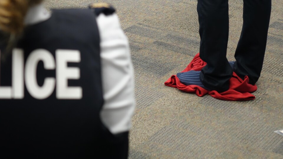 Un homme se tient sur une petite couverture pliée qui figure une réserve autochtone au cours d'une formation de sensibilisation organisée par la GRC.