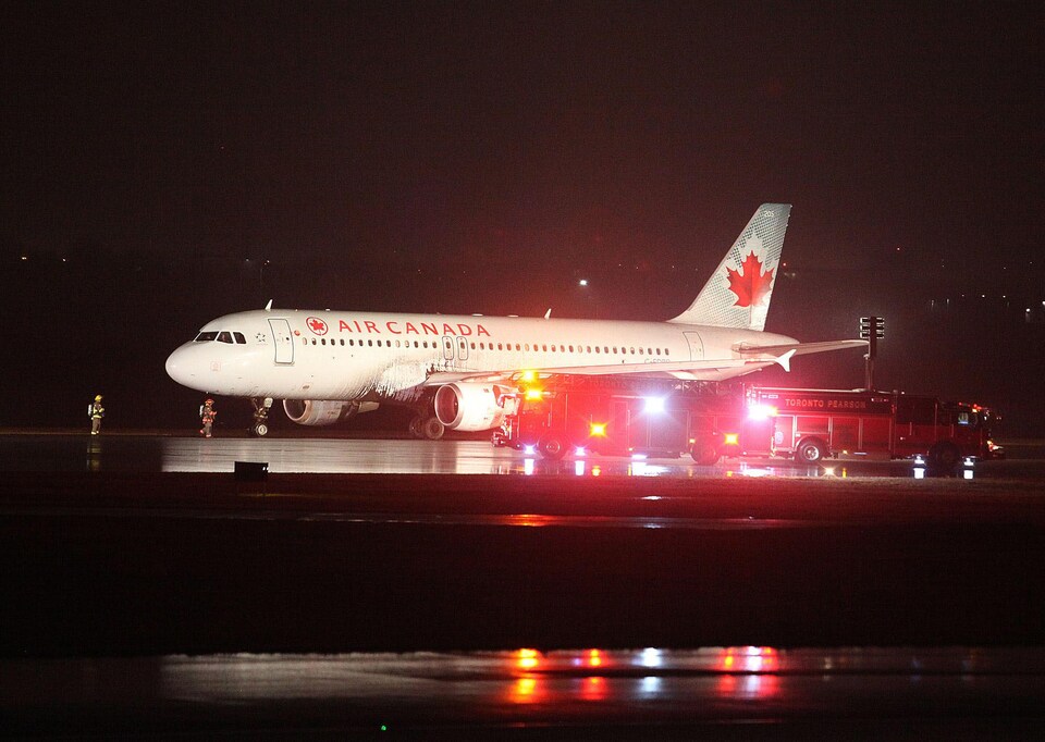 Un avion d'Air Canada sur le tarmac de l'aéroport Pearson, de Toronto, avec des équipes d'urgence qui l'entoure.