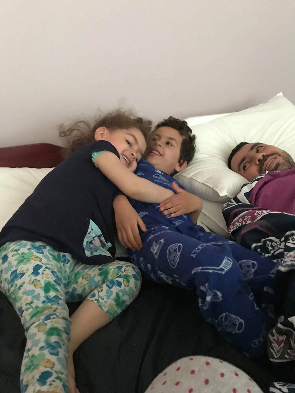 Un homme est entouré de ses enfants dans un lit.