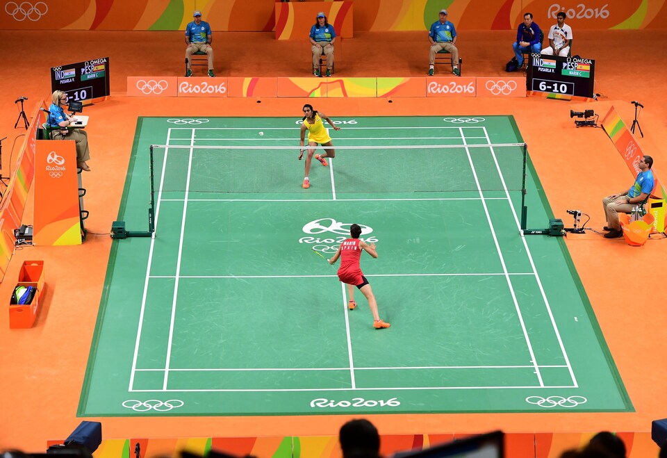 Match de badminton en cours aux Jeux olympiques. On voit l'ensemble du terrain et les deux joueuses en action.