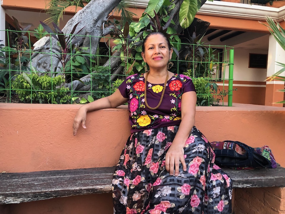 Bettina Cruz, vêtue du costume traditionnel, est assise sur un banc.