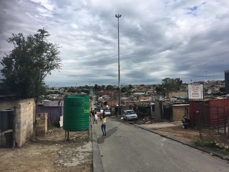 Des maisons petites et rudimentaires pressées les unes contre les autres, des déchets sur le sol.