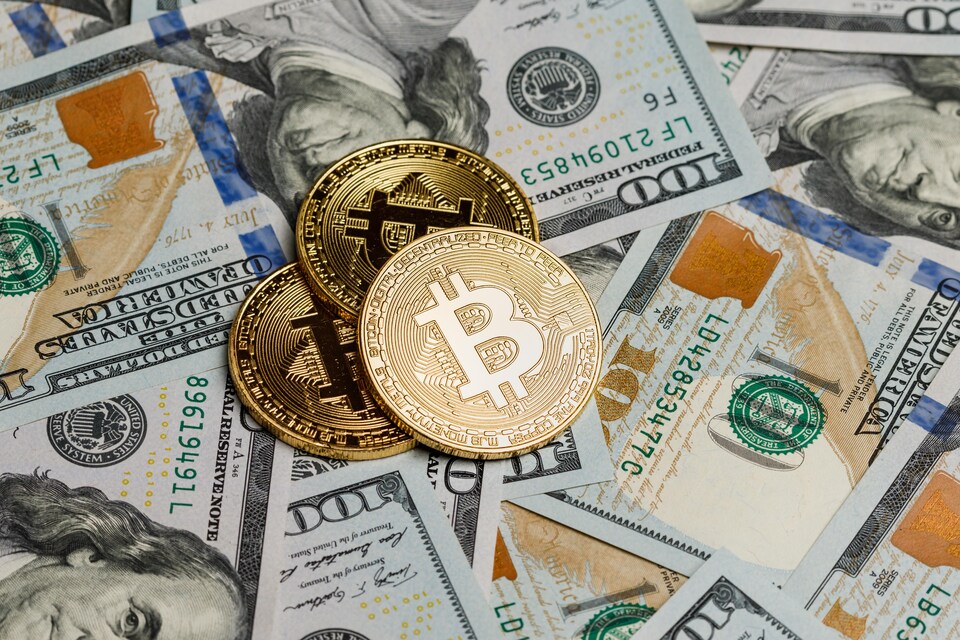 Des bitcoins sont déposés sur des billets de 100 $ américains.