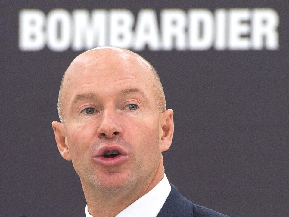 Alain Bellemare, PDG de Bombardier inc. devant une affiche de l'entreprise.