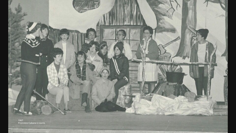 Une photo en noir et blanc d'un groupe de francophones rassemblés pour faire une cabane à sucre. 