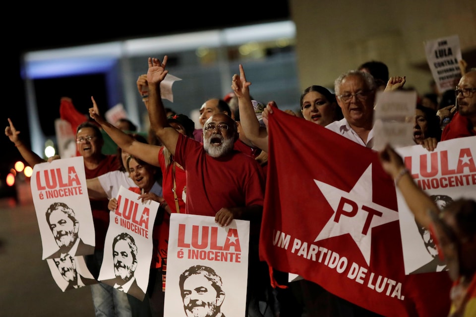 Des manifestants tiennent des affiches soutenant Lula et chantent un slogan, le bras dans les airs.