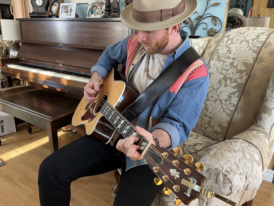 L'artiste joue de la guitare dans un salon.