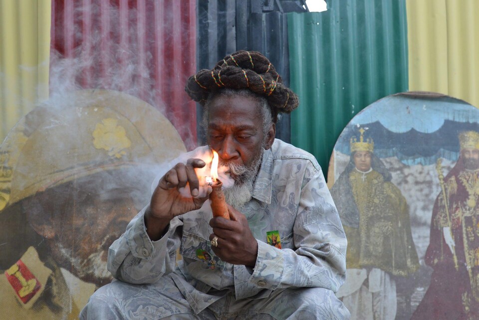 Bunny Wailer allume une pipe.