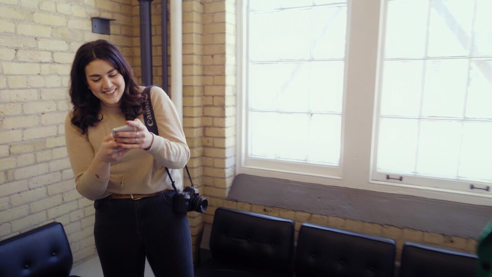 Une femme sourit en utilisant son téléphone.