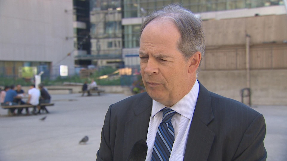 Carol Jolin, président de l'AFO dehors en entrevue avec Radio-Canada, il porte un veston noir, une chemise blanche et une cravate rayée bleue