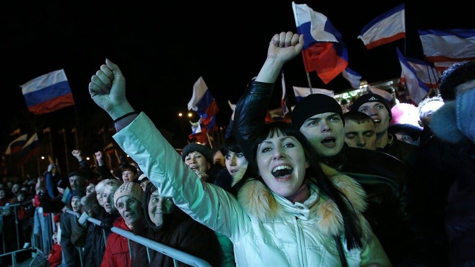 Des gens célèbrent en brandissant le drapeau russe dans les rues de Simféropol, en Crimée, le 16 mars 2014.