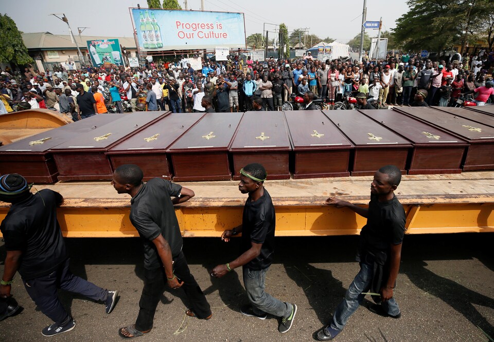 Des hommes marchent à côté de cercueils de victimes des milices peules à Makurdi, au Nigeria, le 11 janvier 2018. 