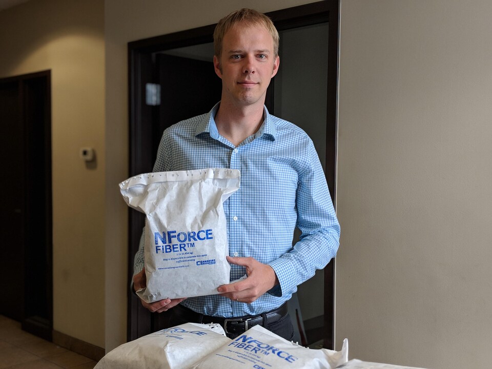 Portrait d'un homme blond qui tient dans ses mains un sac de NForce-Fiber qui a été envoyé en Chine.