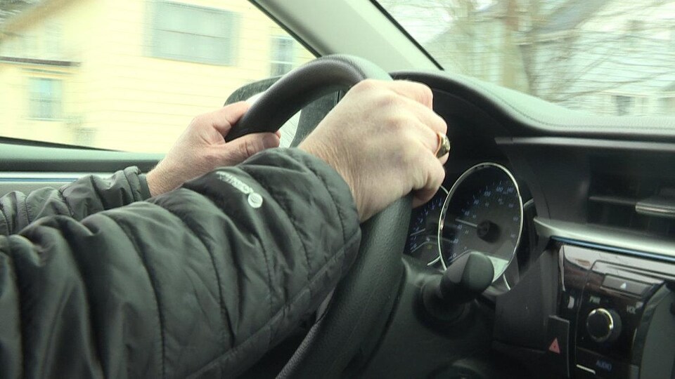 Les mains d'un homme sur le volant d'une voiture.