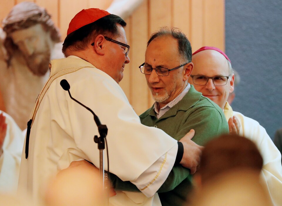 Le cardinal Cyprien Lacroix donne l'accolade au cofondateur du Centre culturel  islamique de Québec Boufeldja Benabdallah lors d'une messe à Sainte-Foy.