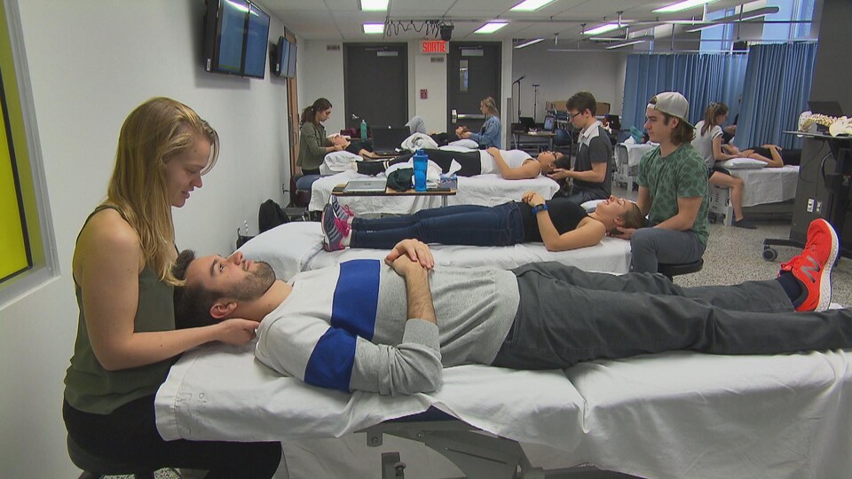 Des étudiants sont en train de traiter leur patient coucher sur un lit.