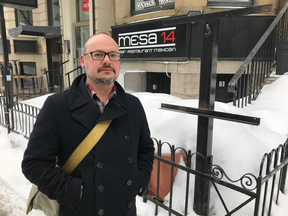 Mike Cloghezy à l'extérieur et portant un manteau noir devant son restaurant fermé et enneigé