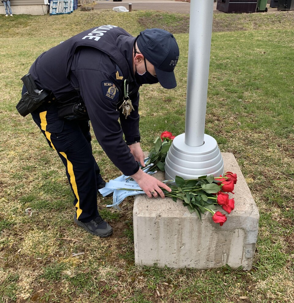 Un gendarme dépose une gerbe de fleurs.
