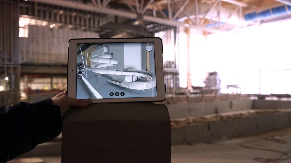 L'image de la glissoire sur une tablette numérique est superposée au chantier.                         