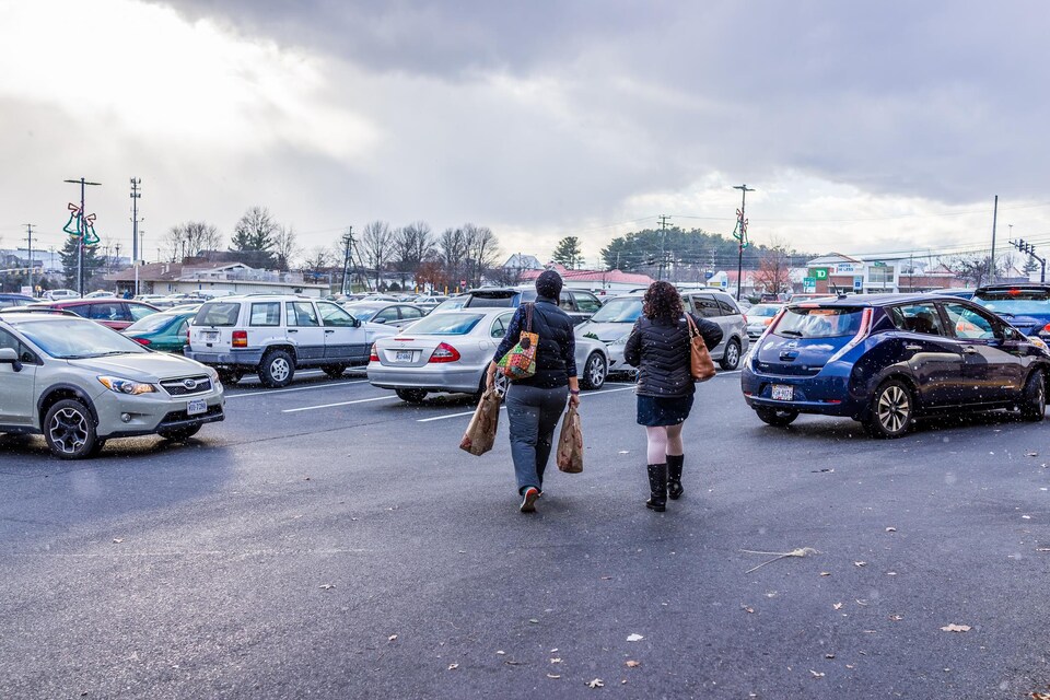 Deux femmes marchent dans un stationnement d'un centre commercial.