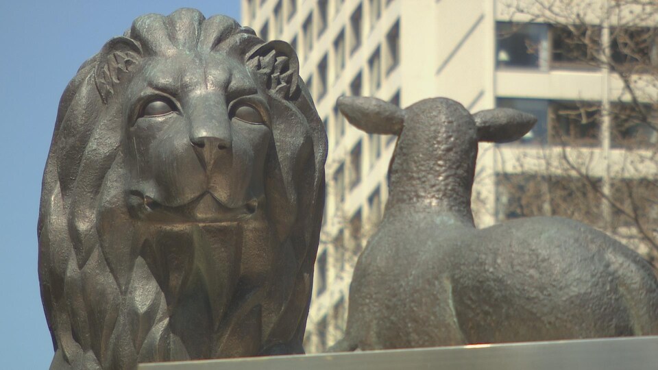Une statue d'un lion géant qui regarde un agneau