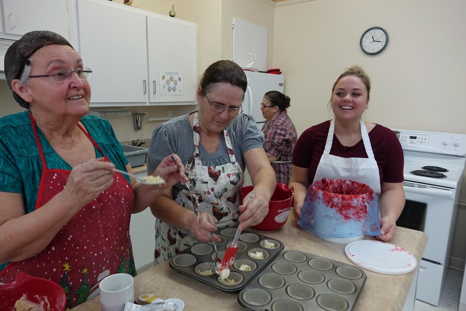 Des femmes rigolent en confectionnant des muffins.